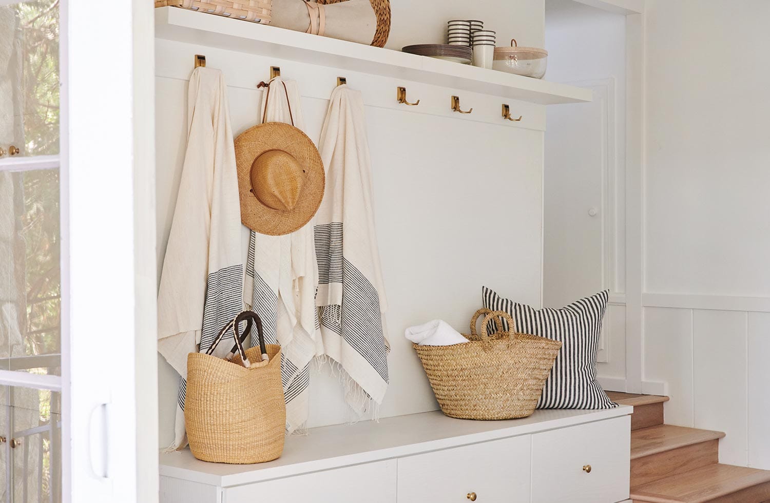 Entryway mudroom with bench seating and storage space in a white finish by California Closets