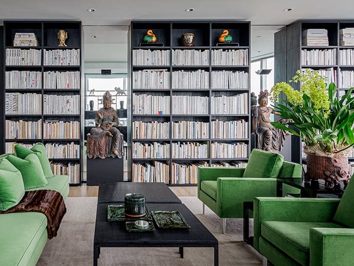 Library with floor to ceiling bookshelves and display cases in a dark wood finish by California Closets